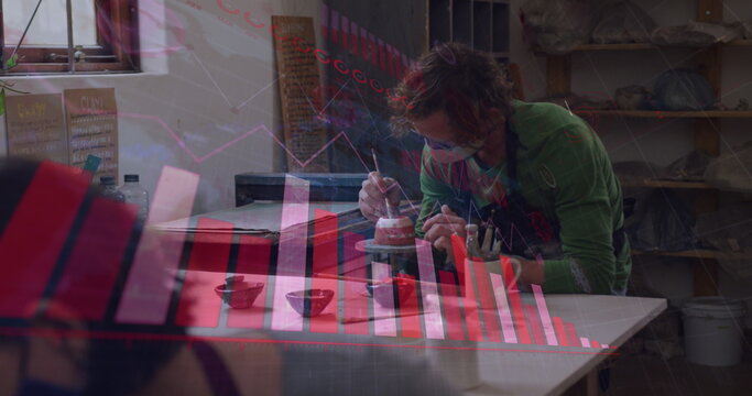 Image of covid 19 cells and statistics over man working in pottery studio wearing face mask - Powered by Adobe