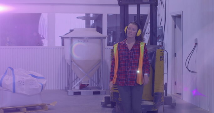 Image of glowing light over caucasian woman working in warehouse