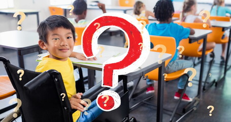 Image of question marks over smiling asian schoolboy in wheelchair in classroom