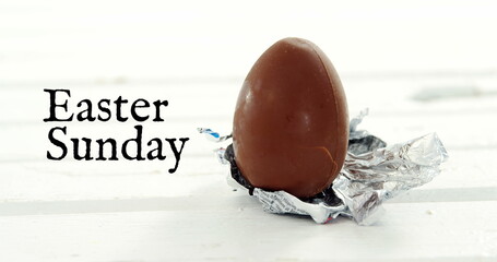 Naklejka premium Image of easter sunday over chocolate egg on white background