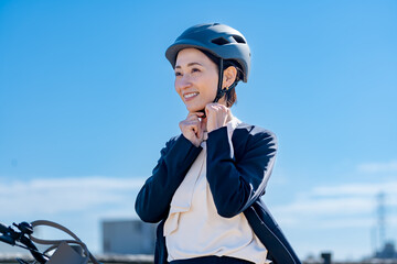 ヘルメットをつけ自転車に乗る日本人女性