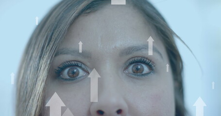 Upward data arrows over eyes of smiling biracial casual businesswoman in office