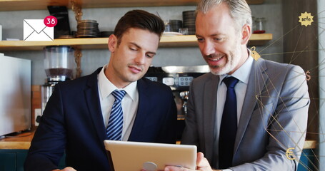 Image of digital interface with business icons over two businessmen using digital tablet