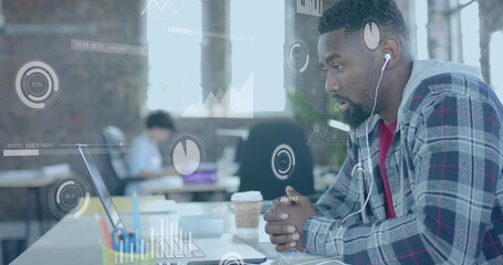 Image of data processing over african american businessman using laptop in office