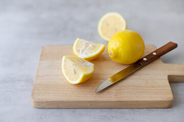 Group of yellow lemon slices on a cutting board on a gray table