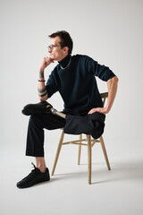 Studio portrait of a successful happy tattooed one legged disabled young male amputee with prosthetic leg wearing casual dark blue clothing. 
