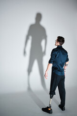 Studio portrait of a successful happy tattooed one legged disabled young male amputee with prosthetic leg wearing casual dark blue clothing. 
