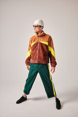 studio portrait of successful happy  tattooed one-legged disabled young man with amputee leg with prosthesis fashionably dressed in bright colored youth street style clothes 