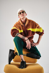 studio portrait of successful happy  tattooed one-legged disabled young man with amputee leg with prosthesis fashionably dressed in bright colored youth street style clothes 