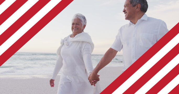Image of flag of united states of america over senior biracial couple holding hands on beach