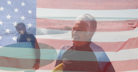 Naklejka premium Image of flag of united states of america over senior biracial couple with surfboards on beach