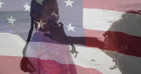 Image of flag of united states of america over biracial mother with daughter on beach