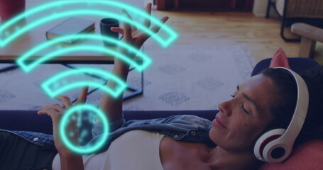 Image of biracial woman using headphones and wifi icons - Powered by Adobe