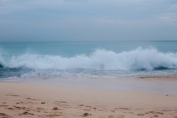 Fototapeta na wymiar A big blue wave near the shore. Ocean view from the sand beach