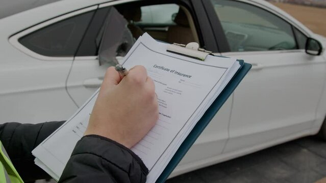 Car parked with a broken window. an insurance questionnaire is presented in the foreground, against the background of a white car with a broken window.