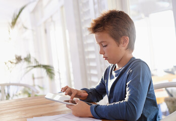Child, tablet and notes in house for homework, elearning and games on table with internet and...