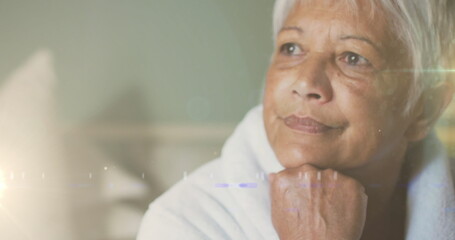 Image of glowing lights over thoughtful senior woman in background