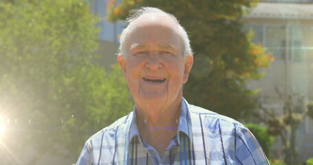 Image of glowing lights over smiling senior man and trees in background