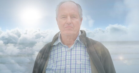 Image of glowing light over serious senior man over clouds
