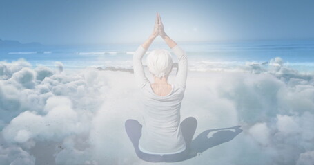 Image of glowing light over senior woman practicing yoga by seaside