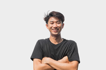 A young Asian man in his 20s wearing a black t-shirt stands confidently with his arms crossed over...
