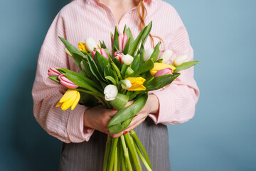 girl with a spring bouquet of tulips on a clean blue background, spring flowers