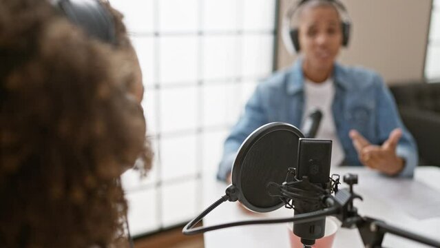 In the heart of the action, smiling reporters work together wearing headphones, speaking live inside the radio studio during an intense interview
