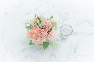 Top view of Pastel pink flowers and candle on a white marble table. Special day or valentines day background with copy space.