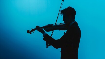 Classic musical performance concept: elegant man in black suit playing violin against vivid blue background