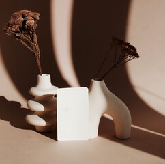 Blanks paper mockup ,modern beige vasen with dry grass , sunlight shadow on beige background.Copy...