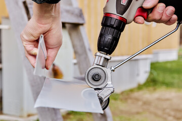 Drill attachment for cutting sheet steel is equipped with rotating metal gearheads, worker cuts...