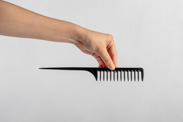 Black hair comb in hand isolated on white background