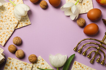 Matzo, eggs, nuts, flowers and hanukkiah on purple background, space for text