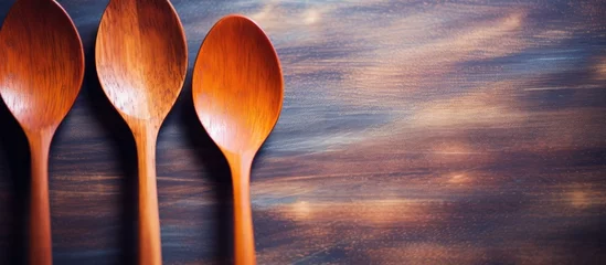 Foto op Plexiglas Three wooden spoons, a type of kitchen utensil, are neatly arranged in a row on a table made of wood. The rustic setting contrasts beautifully with the clear sky outside © 2rogan