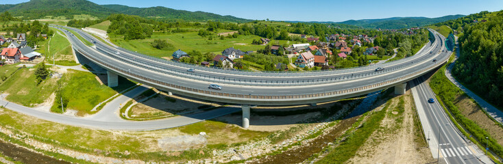 New elevated highway bend over an old Zakopianka road in Lubien village in Poland. Wide aerial panorama