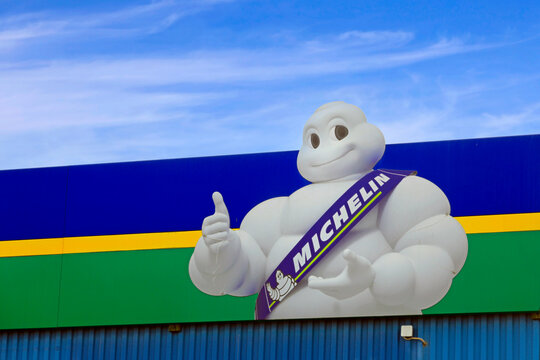 Michelin Man or Bibendum, the official mascot of the French Michelin tire company, with blue sky clouds background. 