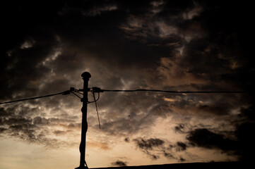 silhouette of electric poles and cables against the orange sky in the morning