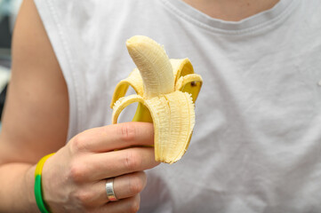 Banan trzymany w dloni, mężczyzna je banana - obrazy, fototapety, plakaty