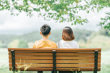 ベンチに座るカップルの後ろ姿