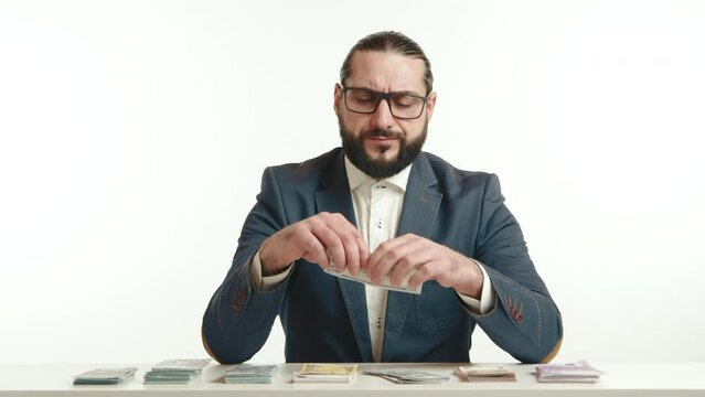 In a bold act of defiance against materialism, a businessman in a navy suit tears a hundred-dollar bill, questioning the true value of money in a thought-provoking portrayal. Camera 8K RAW. 