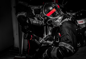 European firefighters in full exercise in a narrow and smoky environment, predominant red color - obrazy, fototapety, plakaty