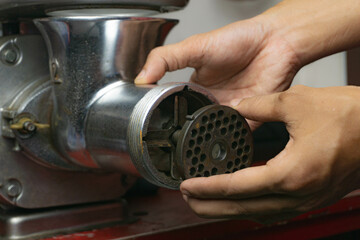 a man attaching grinder plate to a meat grinder
