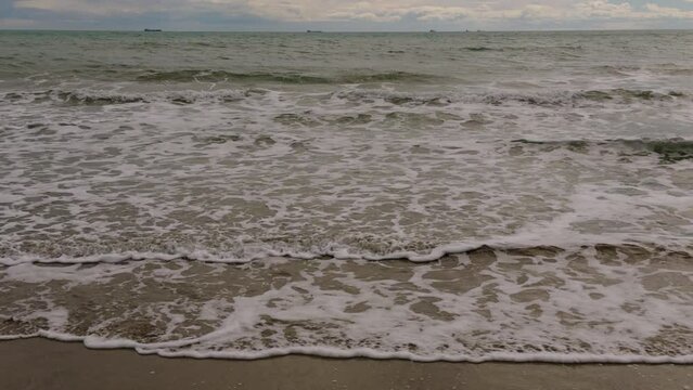 A walk on a sandy beach in Spain. A warm winter day in the sand dunes of Benicassim. The ships are anchored in the roadstead in the port of Grao on the horizon line. Castellon