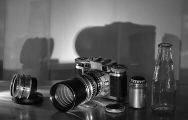 Comeback of film photography concept with vintage range finder analog camera,lens,film canister and camera film, black and white,free copy space - obrazy, fototapety, plakaty