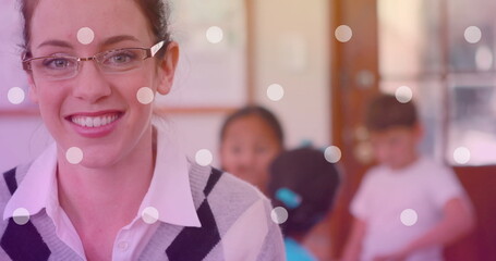 Image of white spots over smiling caucasian female teacher with diverse schoolchildren