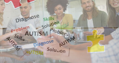 Image of colourful puzzle pieces and autism text over business colleagues using tablet