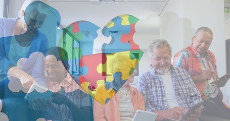 Image of colourful puzzle pieces heart over senior friends using electronic devices