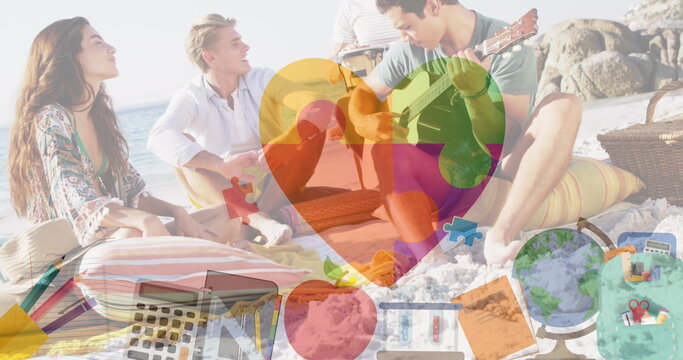 Image of colourful puzzle pieces and school icons over happy friends at summer beach party