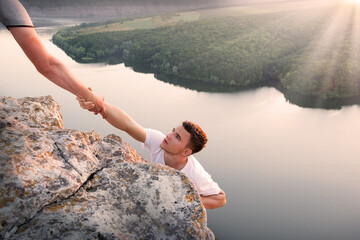 Man help his friend to climb on the rock