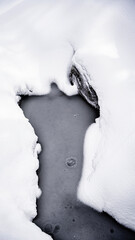 An ice hole in the middle of a mountain snowy forest in winter.
